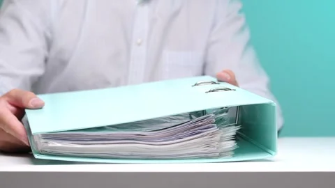 Person's hands preparing to file numerous documents and papers into a light Stock Footage 342769759