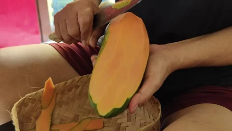 Person's hands separating the papaya skin and flesh with a knife Stock Footage 274038947