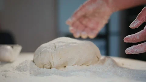 Person's hands shape dough on a floured counter Stock Footage 336047391