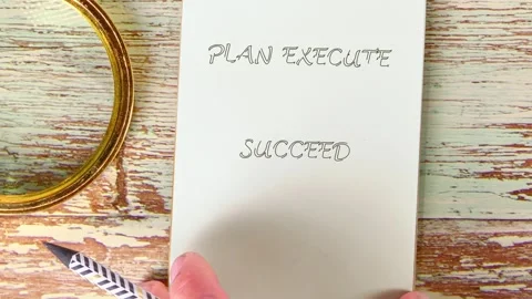 A persons hands show the phrase Plan Execute Succeed on paper and a small Video stock 332537193