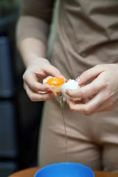Person's hands skillfully separating egg white from yolk using eggshell hal.. Stock Photos