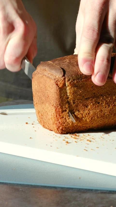 Person's hands slicing freshly baked bread loaf Stock Footage 337830543