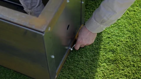 A person's hands tightening a nut on a bolt with a wrench, assembling a metal Stock Footage 323878341