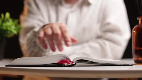 Person's hands turning pages of an open book on a table Stock Footage 339213437