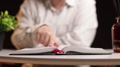 Person's hands turning pages of an open book on a table with plants and bottles Stock Footage 339213514