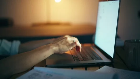 Person's hands typing on a laptop keyboard at night. Stock Footage 247041248