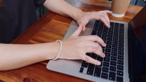 Person's hands typing on a laptop keyboard, using technology for remote work or Stock Footage 334457851