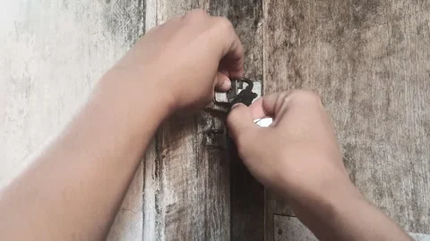 Person's hands use a key to unlock a weathered wooden door Stock Footage 313100549