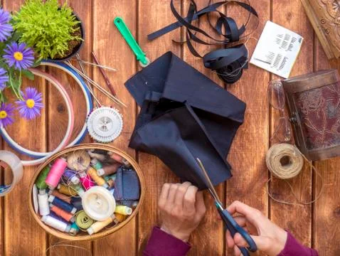 Person's hands working at the knitting workshop table with scissors and cloth Stock Photos