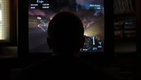 Person's head in front of screen as he plays a driving video game Stock Footage 8687072