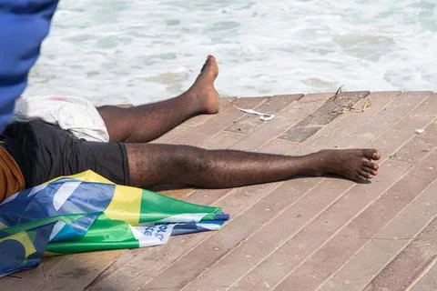 A persons legs resting on a seaside deck Stock-Fotos
