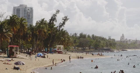 Persons relaxing lying around on the shore at Balneario del Escambron, San Stock Footage 165194082