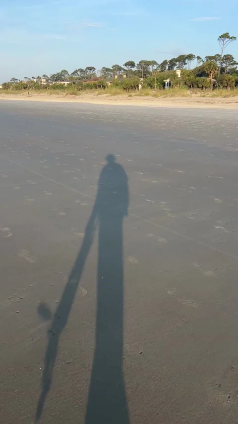 Persons shadow on the beach sand while walking Stock Footage 196928556