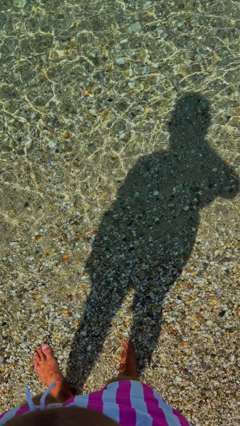 Person's Shadow Cast on Clear Shallow Water Over Colorful Pebbles Stock Footage 344371385