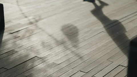 A person's shadow walk on a wooden deck with their legs raised high. Video stock 328041334