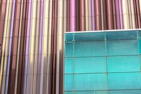 Perspective angled shoot of perforated facade before colorful wall Stock Photos