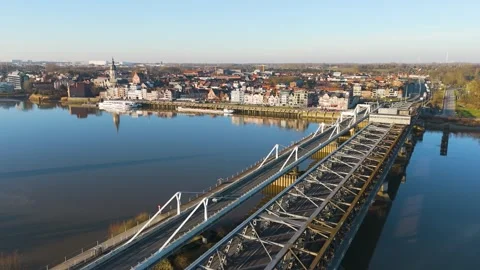 Perspective displays parallel road steel railway bridge crossing glassy river Stock Footage 328193301