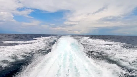 Perspective of the ocean waves blending with a boats wake under a cloudy sky Stock Footage 279627647