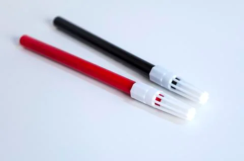 Perspective open shoot of red and black magic marker on white surface Stock Photos