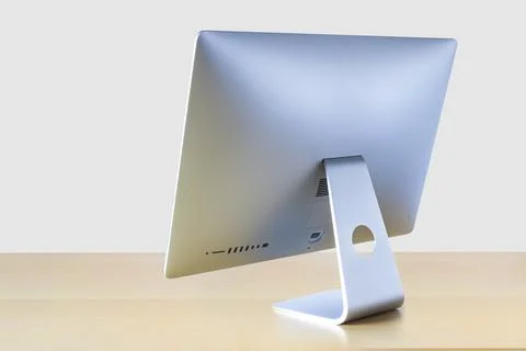 Perspective rotated back view of an computer on a wooden table with a white b Stock Photos