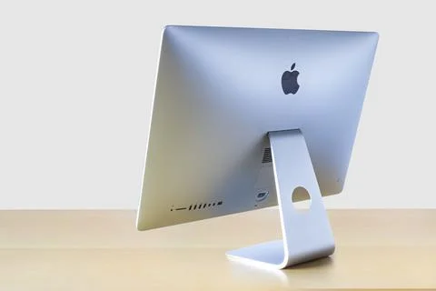 Perspective rotated back view of an iMac computer on a wooden table with a white Stock Photos