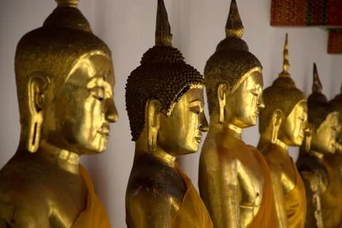 Perspective view along row of sitting golden Buddha statues Stock Photos