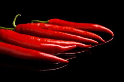 Perspective view of chilli red peppers isolated on black background Stock Photos