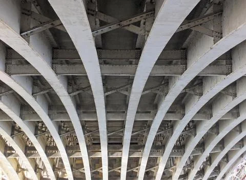 Perspective view of curved arch shaped steel girders under an old road bridge Stock Illustration