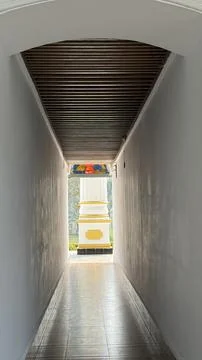 A perspective view down a long, white, and narrow hallway, culminating in an  Foto stock