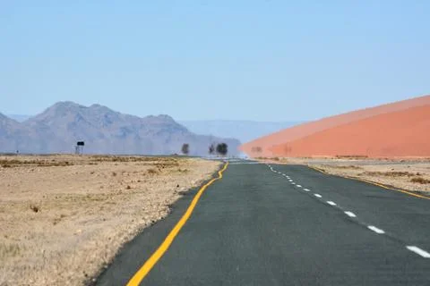 Perspective view of an empty asphalt road in a desert area between small hill Stock Photos