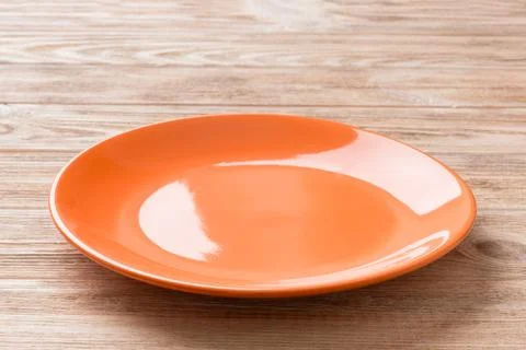 Perspective view of empty orange plate on cement background. Empty space for  Stock Photos