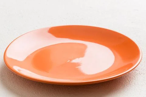 Perspective view of empty orange plate on cement background. Empty space fo.. Stock Photos