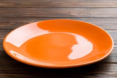 Perspective view of empty orange plate on wooden background. Empty space fo.. Stock Photos