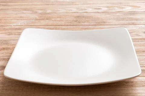 Perspective view of empty square plate on wooden background. Empty space fo.. Stock Photos