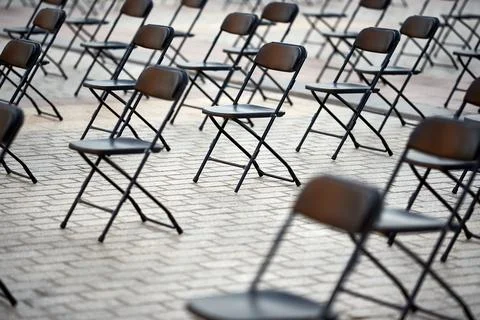 Perspective view of multiple empty black metal folding chairs on cobblestone  Foto stock