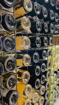 Perspective view of multiple wine bottles stored in a metal rack in a dark .. Stock Photos