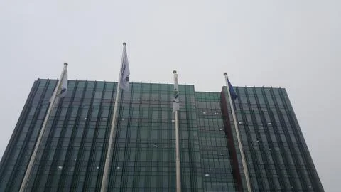 Perspective view of a skyscraper building with flags in front of it. Stock Photos