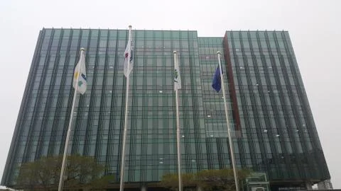 Perspective view of a skyscraper building with flags in front of it. Fotos de archivo