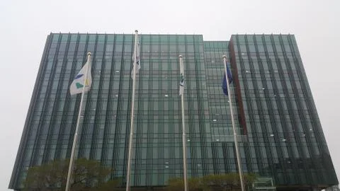 Perspective view of a skyscraper building with flags in front of it. Stock Photos