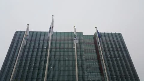 Perspective view of a skyscraper building with flags in front of it. Stock Photos