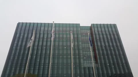 Perspective view of a skyscraper building with flags in front of it. Stock Photos