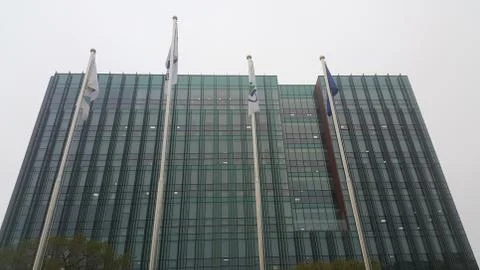 Perspective view of a skyscraper building with flags in front of it. Stock Photos