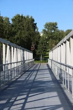 A perspective view walking across a modern pedestrian metal truss bridge lead Stock Photos