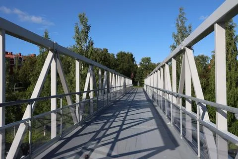 A perspective view walking across a modern pedestrian metal truss bridge lead Fotos de archivo