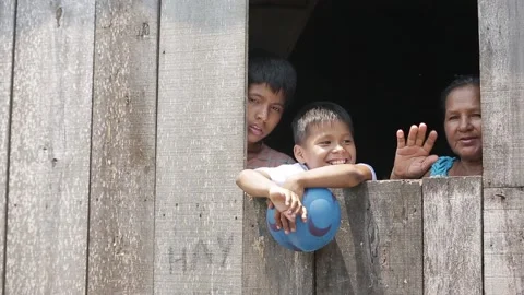 Peruvian children boys wave from the window of a wooden house. slums on water Stock Footage 233288511