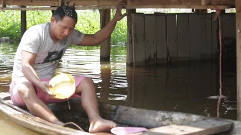 Peruvian man bailing water out of a boat. out of focus 스톡 동영상 233288508