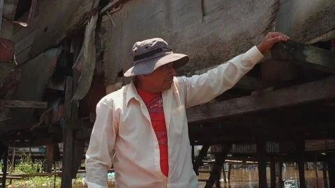 Peruvian man in a hat, stands in a boat near the slums on the water wooden house Video stock 233288657
