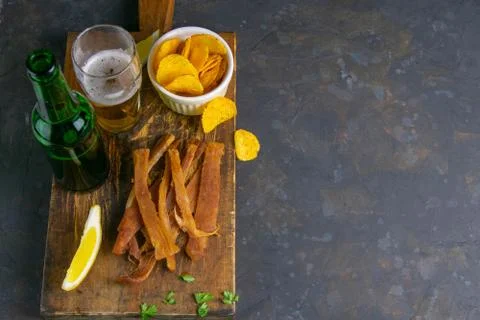 Peruvian squid with beer, lemon and potato chips on dark wooden board. Snack  Stock Photos
