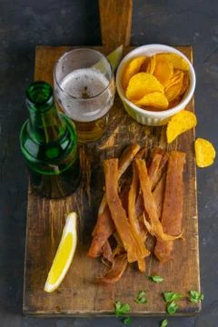 Peruvian squid with beer, lemon and potato chips on dark wooden board. Snack  Stock Photos