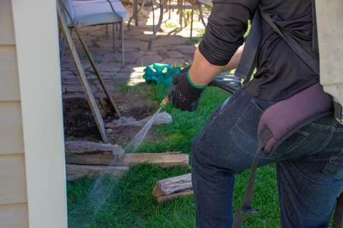 Pest control tech spraying foundation of a house Stock Photos